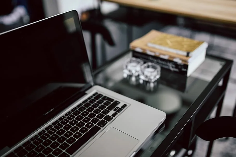 A laptop and books on a wooden desk